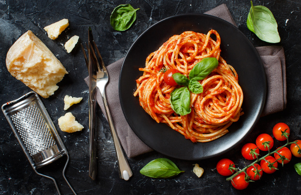 Makaron spaghetti z sosem pomidorowym, bazylią i ser na stół ciemny - Zdjęcie, obraz