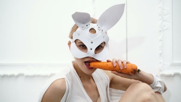 Close up of woman in a mask of hare eating carrots. Halloween party and celebration concept. Concept leather mask BDSM. - Materiał filmowy, wideo