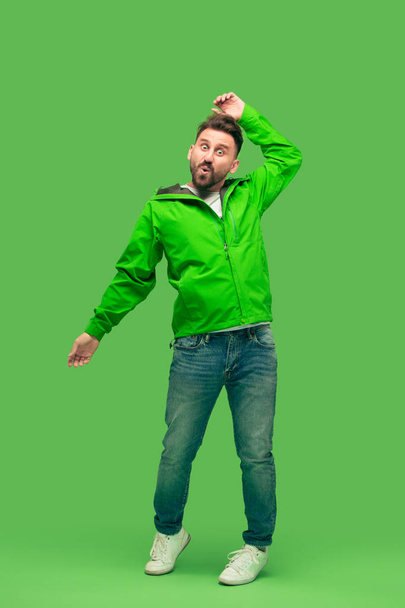 handsome bearded young man looking at camera isolated on green - Foto, afbeelding