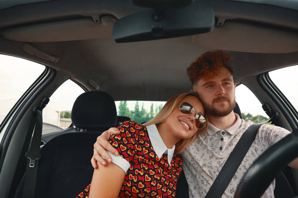 Joven hombre atractivo abrazando a su mujer con afecto mientras conduce el coche
 - Foto, imagen