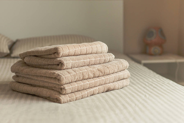 Stack of beige hotel towel on bed in bedroom interior. Vintage toning. Soft focus. - Fotó, kép