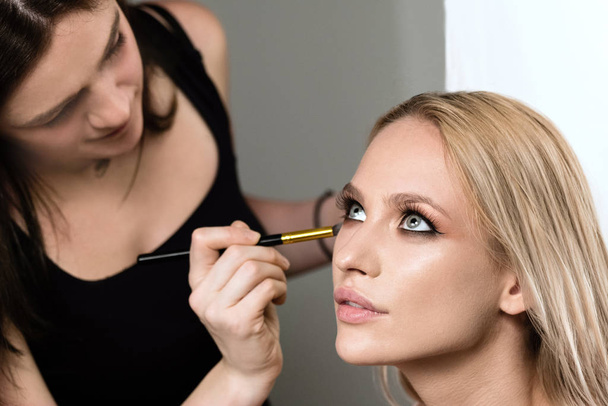 makeup stylist applying makeup on the model closeup beauty face - Photo, image