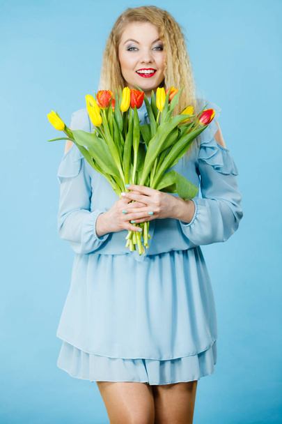 International women day, eight march. Beautiful portrait of pretty woman blonde hair with red yellow tulips, fashion make up, elegant dress. Mother day. On blue - Photo, Image