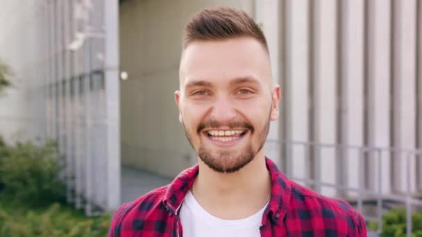 Fiatal férfi szakáll mosolyogva a városban - Felvétel, videó