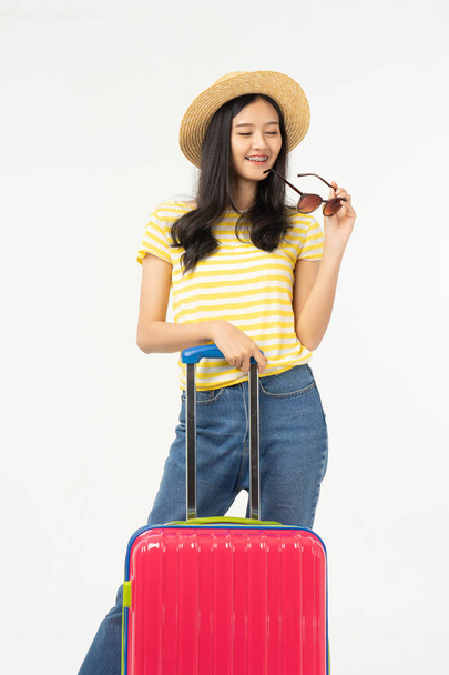 Beautiful young woman smiling and pulling pink color luggage isolated on white background.Woman going to summer vacation.Travel trip funny. - Photo, image