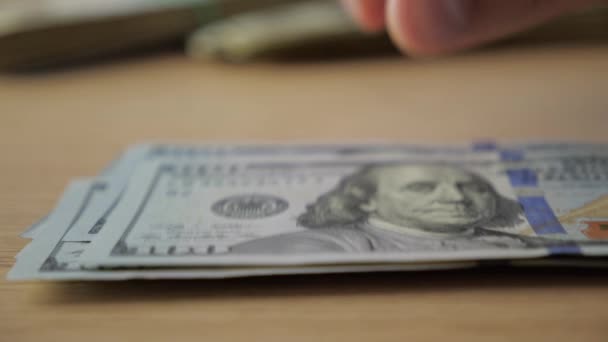 Zbliżenie: businessmans ręce licząc stu dolarowych przy stole - Materiał filmowy, wideo