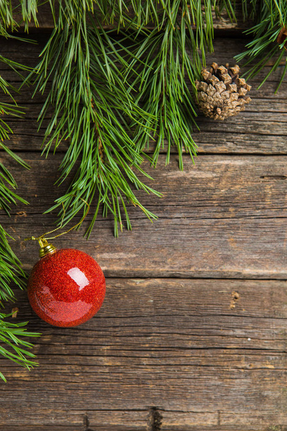 evergreen fir twigs with shiny red baubles and pine cones on old wooden background - Photo, Image