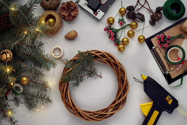 Χριστουγεννιάτικο φόντο με διακοσμητικά, κώνοι γιρλάντα και πεύκα. Δημιουργία στεφάνι φτιαγμένο από κλαδιά χριστουγεννιάτικο δέντρο σε λευκό φόντο. - Φωτογραφία, εικόνα