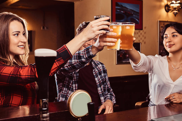 Felices amigos multirraciales haciendo un brindis con cerveza en el bar o pub
. - Foto, Imagen