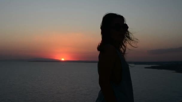 silhouette d'une femme qui se déplace sur un fond de coucher de soleil, une dame danse sur le sable le soir, ses cheveux flottent dans le vent
 - Séquence, vidéo