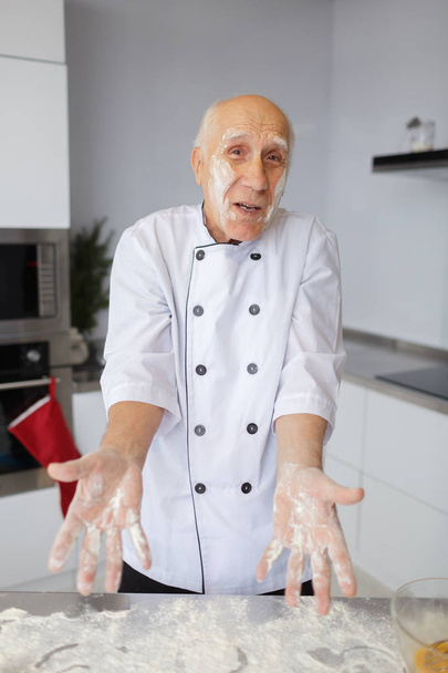Elderly man chef kneading the dough in the kitchen. Cook in flour preparing raw dough for handmade pizza. - Photo, image