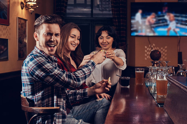 Alegre amigos multirraciales disfrutando de bebidas en el bar o pub
. - Foto, imagen