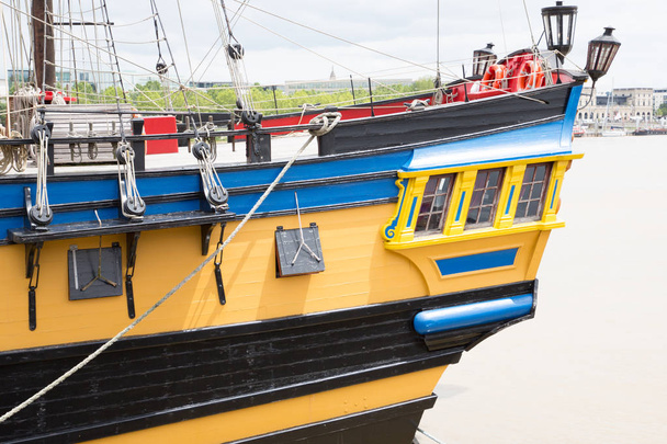 una vista desde la parte trasera de un barco réplica amarilla y azul velas
 - Foto, imagen