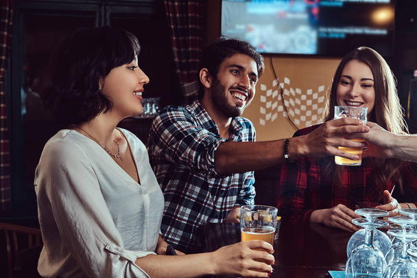 Молодые многорасовые друзья в баре. бармен дает бокал пива клиенту в пабе
. - Фото, изображение