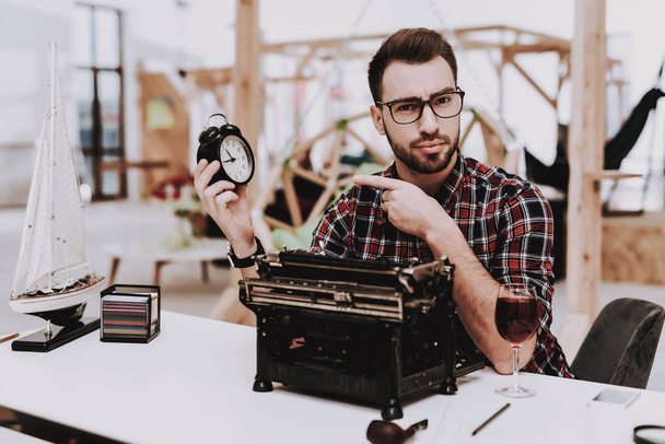 Alarm Clock. Old Typewriter. Pipe for Smoking. Young Male. Businessman. Working in Office. Creates Ideas. Eyeglasses. Workplace. Project. Sit. Brainstorm. Work. Office. Creative Worker. Inspiration. - Foto, imagen