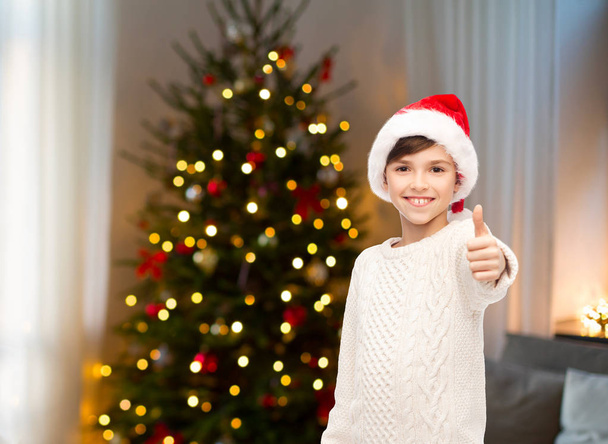 happy boy in santa hat showing thumbs up - Zdjęcie, obraz