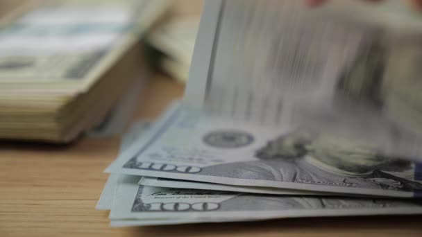 Primer plano de las manos de los empresarios contando billetes de cien dólares en una mesa
 - Imágenes, Vídeo