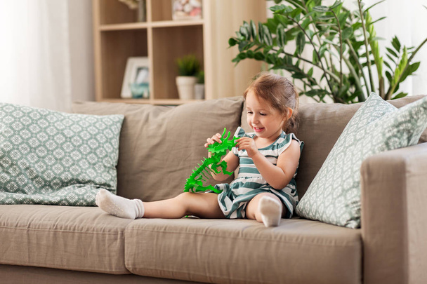 happy baby girl playing with toy dinosaur at home - Photo, Image