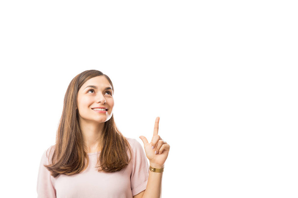 Mujer joven sonriente mostrando espacio en blanco sobre fondo blanco
 - Foto, Imagen