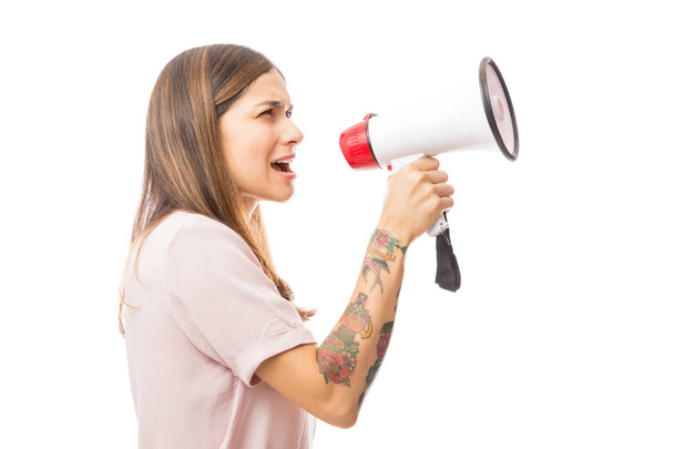 Side view of young woman making announcement using megaphone over white background - Photo, Image