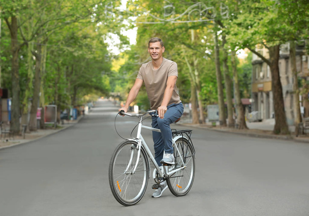 Handsome man riding bicycle outdoors on summer day - Foto, Bild