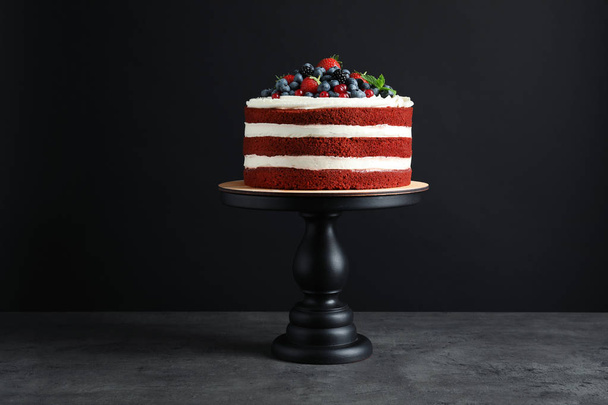 Stand with delicious homemade red velvet cake on black background - Foto, Imagen