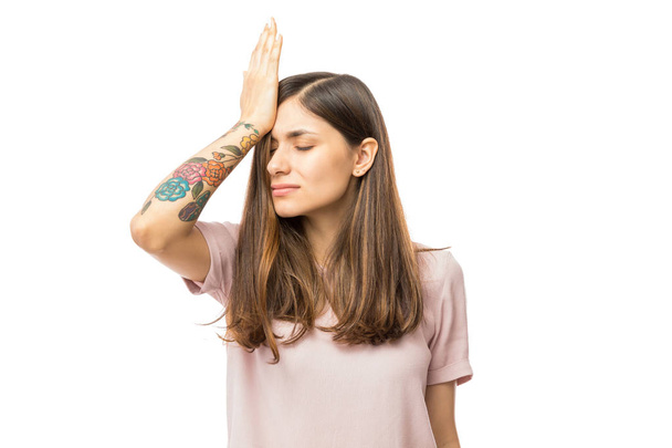 Жінка усвідомлює помилку і тримає руку на голові на білому тлі
 - Фото, зображення