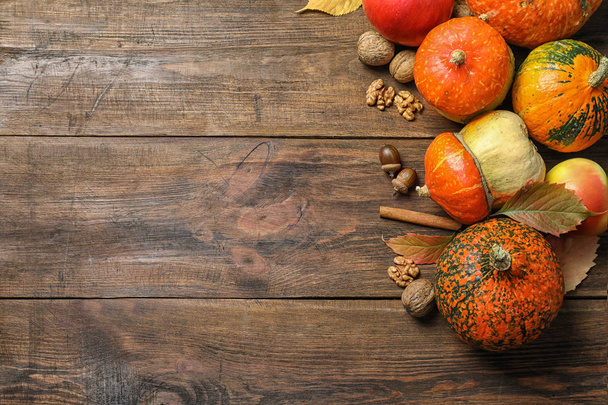 Different pumpkins on wooden background, flat lay composition with space for text. Autumn holidays - Фото, изображение