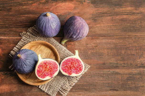 Plate with fresh ripe figs on wooden background, top view. Space for text - 写真・画像
