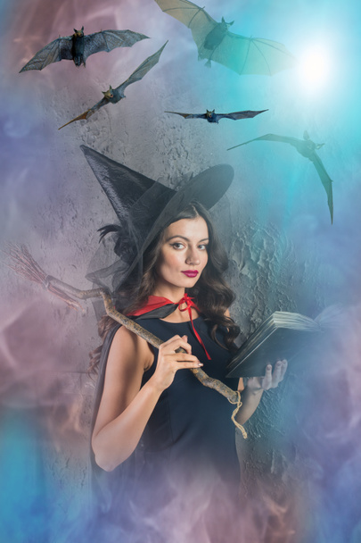 Halloween czarownica trzyma książkę z nietoperzy na mglisty tło gradientowe - Zdjęcie, obraz