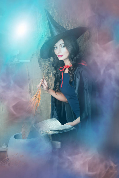 Halloween strega tenendo libro e piuma su sfondo viola fumoso
 - Foto, immagini