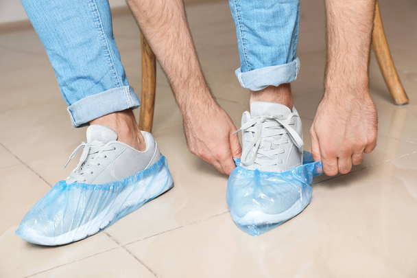 Man putting on blue shoe covers, closeup - Foto, afbeelding