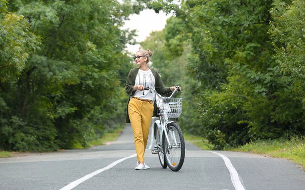 Beautiful woman in casual outfit with bicycle outdoors - Zdjęcie, obraz