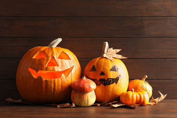 Halloween pumpkin head jack lanterns on table against wooden background - Photo, image