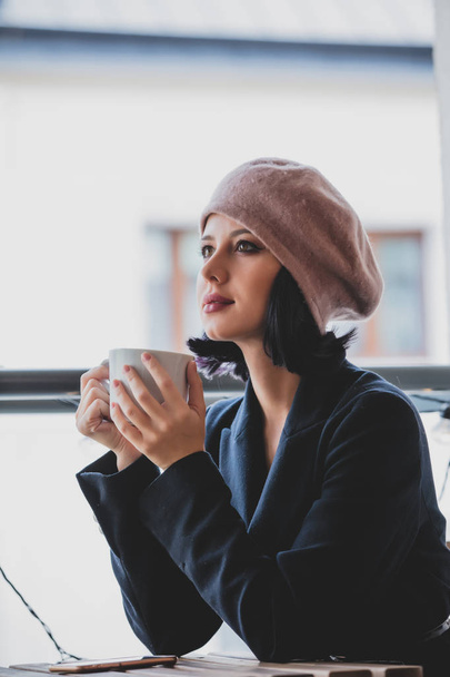 Retrato de uma jovem com xícara de café sentado à mesa e relaxar
. - Foto, Imagem
