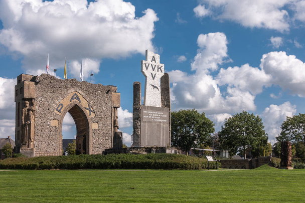 Diksmuide, Flanders, Belgium - September 15, 2018: PAX Gate and crypt ruin at IJzertoren plain. Gray and brown stones, AVV-VVK symbol on white cross, Green lawn with dark green trees under blue sky with white clouds. - Photo, Image