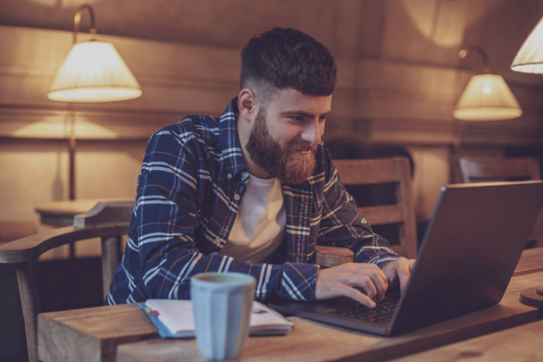 Jovem profissional navegando na Internet em seu laptop em um café
 - Foto, Imagem