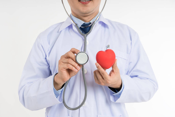 Male doctor in white uniform hold and use stethoscope to check up heart red toy heart. Cardio therapeutist, physician make cardiac physical, heart rate measure, arrhythmia concep - Photo, Image