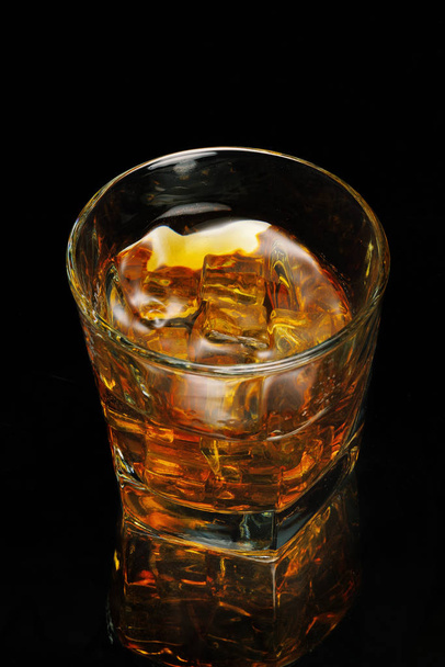 A glass of whiskey on a black background. ice cubes. Isolated - Fotó, kép