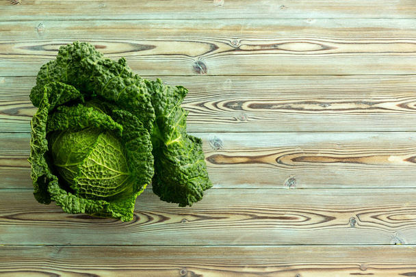 Single large leafy head of dark green lettuce on top of wooden table background. Includes copy space. - Fotoğraf, Görsel