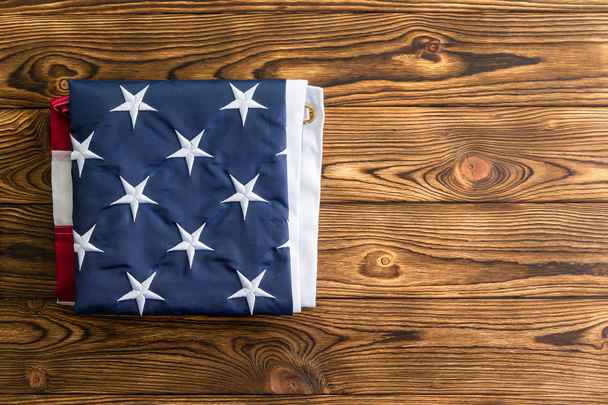 Neatly folded American flag showing the stars representing the original 13 colonies on a wooden table viewed from overhead with copy space - Фото, зображення