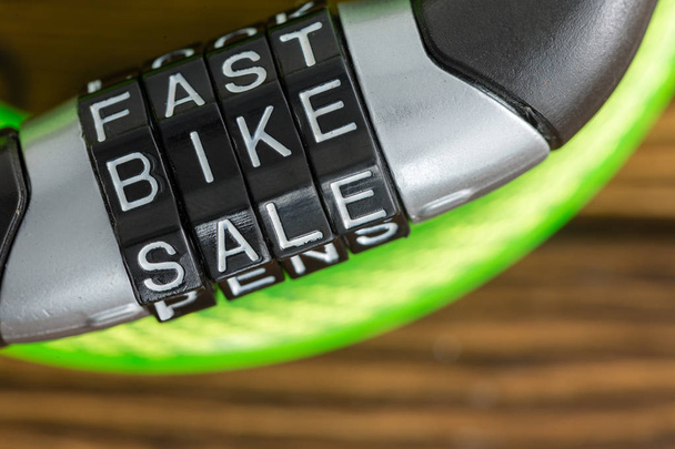 Serrure à vélo à combinaison de lettres avec code - Fast Bike Sale - pour déverrouiller le câble en acier recouvert de plastique dans une image conceptuelle sur bois
 - Photo, image