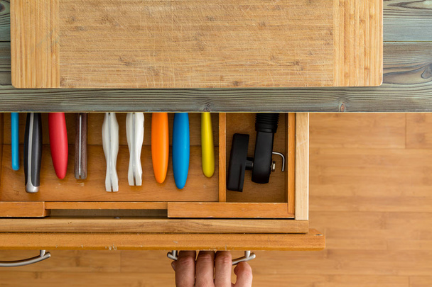 Man or chef opening a knife drawer in a kitchen in an overhead view of the neatly fitted interior of the drawer and a kitchen counter with cutting board - Foto, afbeelding