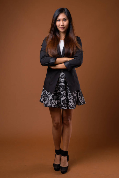 Joven hermosa mujer de negocios asiática contra fondo marrón
 - Foto, Imagen