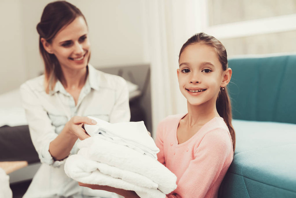 Daughter Helps The Mother With Household Chores. Bright Room. Clean Laundry. Young Helper. Holiday Leisure. Family Relationship Concept. Domestic Problems. White Towels. Parent's Duty. - Foto, imagen