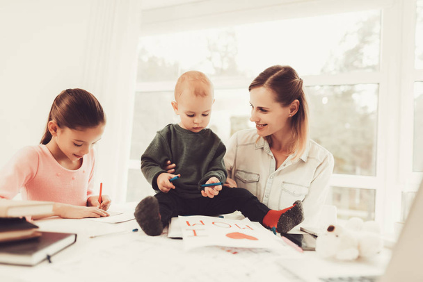 Mom Plays With A Baby. Daughter's Homework Task. Educational Childhood. Studying At Home. Knowledge Receiving. Information Writing. Open Textbook. Smart Kid. Family Holiday Concept. - Valokuva, kuva