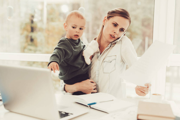 A Woman Works During Maternity Leave At Home. Problems Solving. Official Clothes. Comfortable Environment. Talking On The Phone. Concentrated Worker. Parent Duty. Family Relationship. - Photo, image
