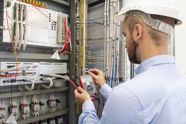 electrician technician in fuse box. Maintenance engineer in control panel. Worker is testing automation equipment. Engineering in electrical station. Electric man with multimeter in hands. Service. - Foto, afbeelding