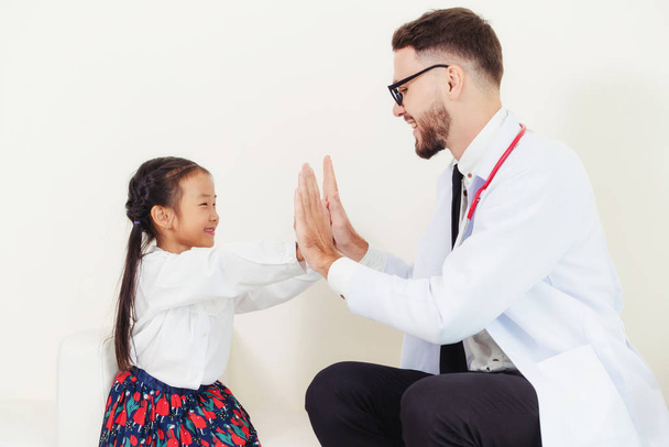 Little kid visit doctor in hospital office. The kid is happy and not afraid of the doctor. Medical and children healthcare concept. - 写真・画像