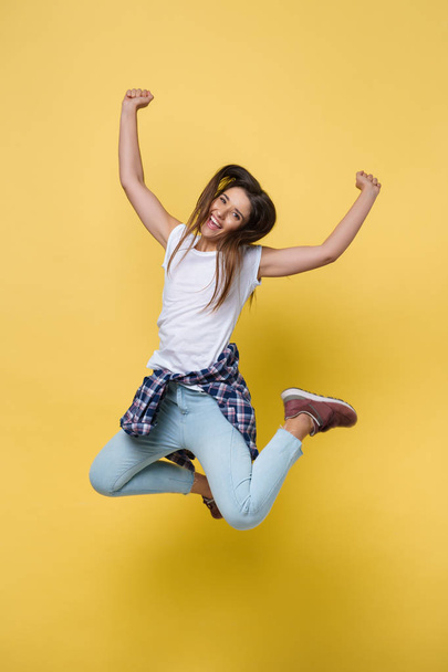 Full length portrait of a cheerful casual caucasian woman jumping isolated over yellow background - Photo, Image